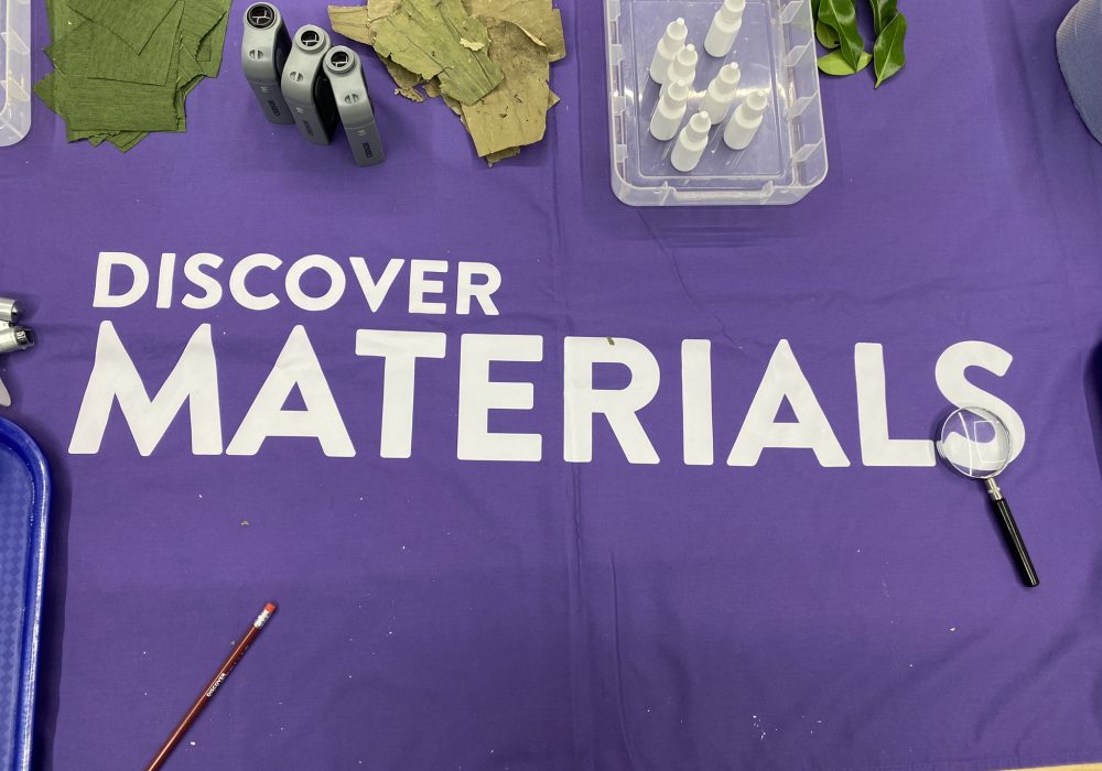 Discover Materials Logo printed on a tablecloth with a range of outreach materials.