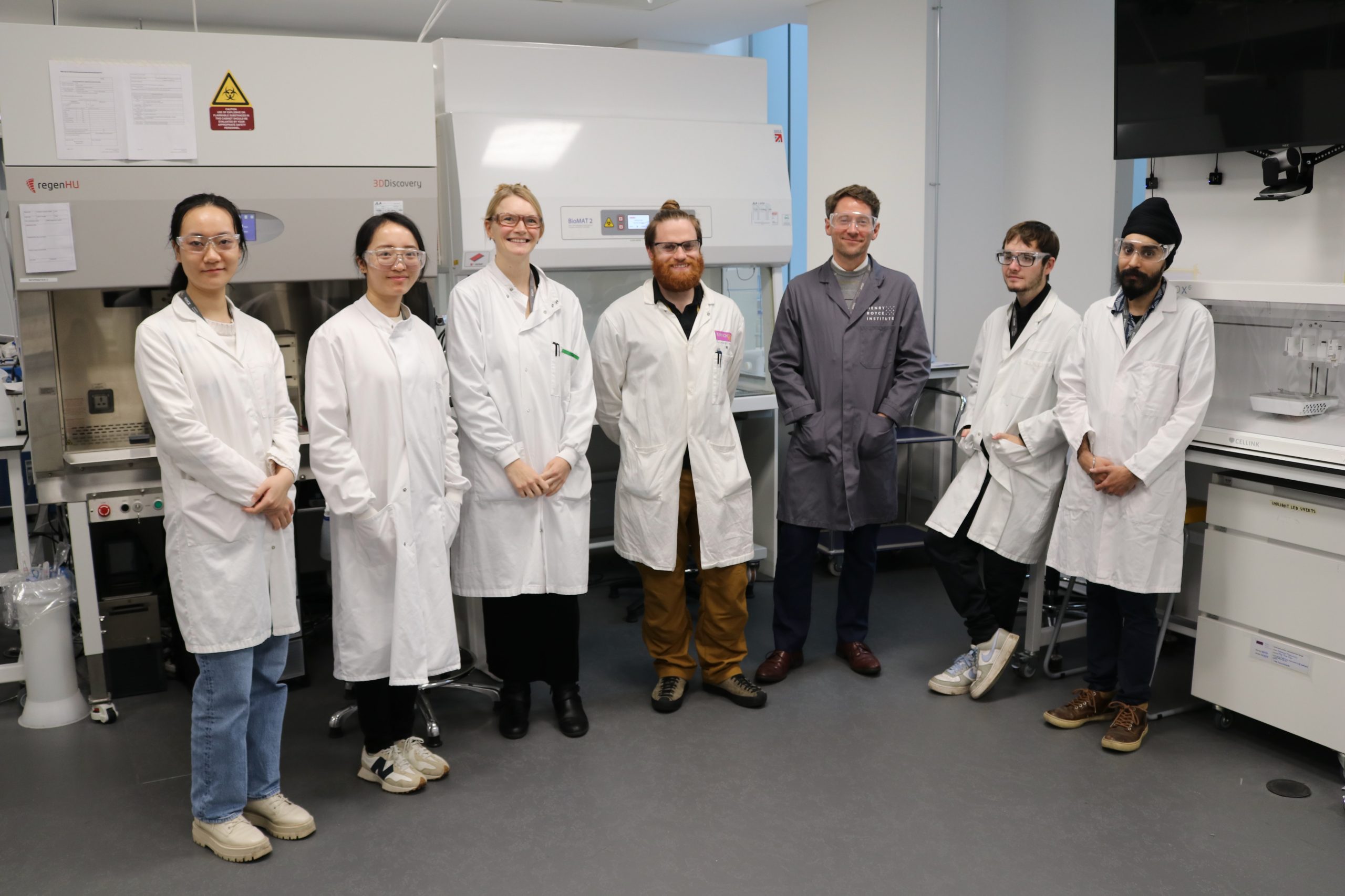 Seven Technical Professionals in lab coats stand in a Biomedical laboratory setting