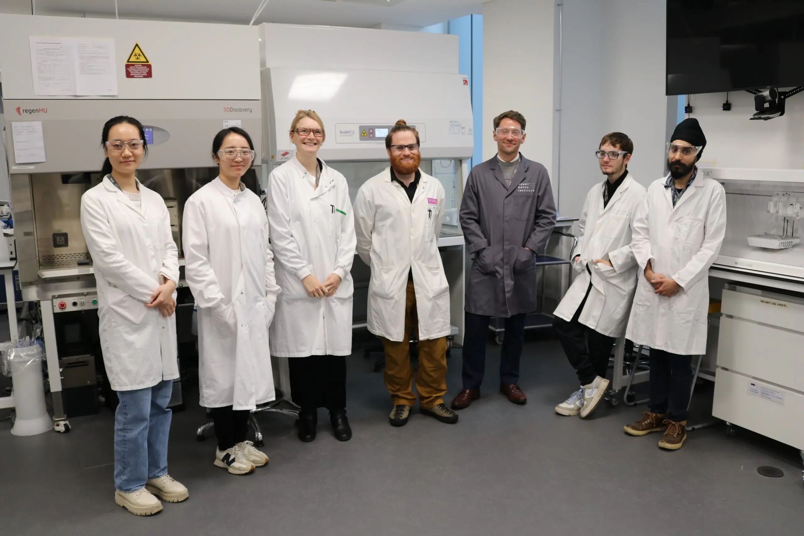 Seven Technical Professionals in lab coats stand in a Biomedical laboratory setting