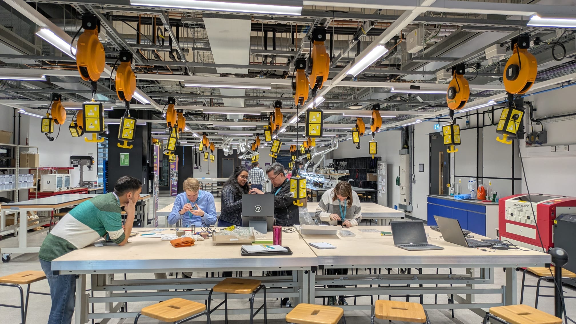 Image taken from the event, Knowledge of the Nanoscale: Developing AFM Activities for Outreach, showing attendees clustered around a table examining scientific equipment.