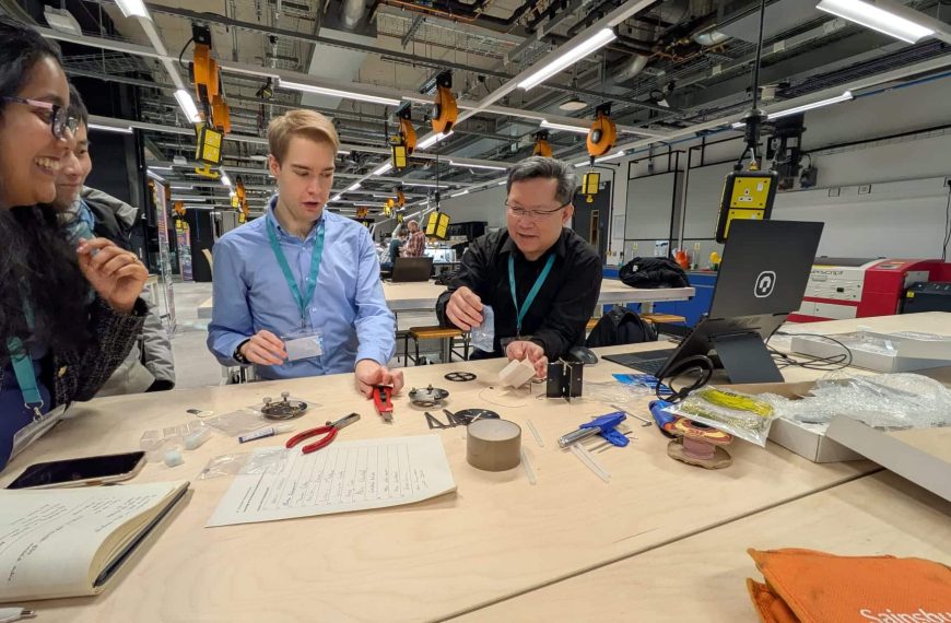 Image from the workshop 'Knowledge of the Nanoscale: Developing AFM Activities for Outreach' showing three people clustered around a table examining scientific equipment.