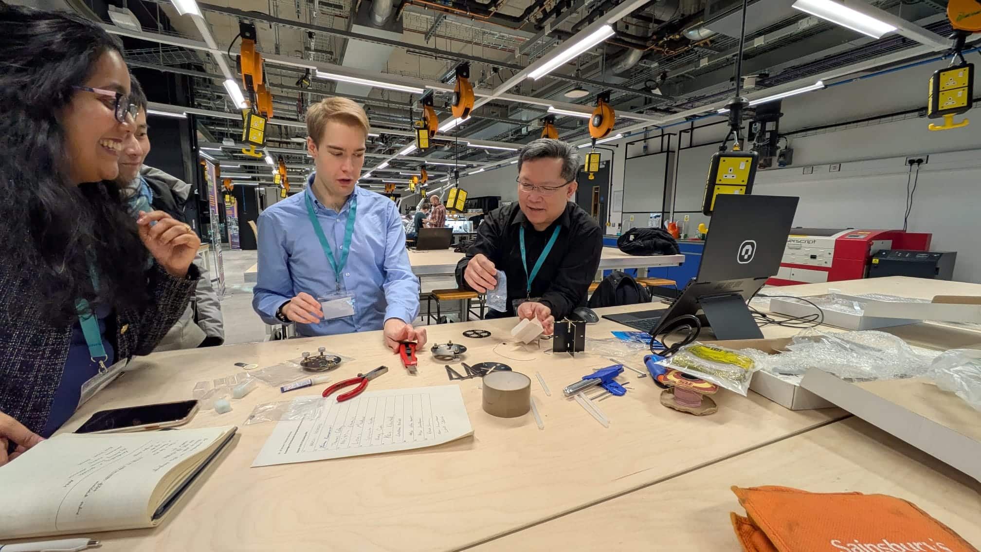 Image from the workshop 'Knowledge of the Nanoscale: Developing AFM Activities for Outreach' showing three people clustered around a table examining scientific equipment.