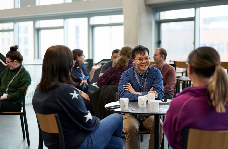 Researchers networking over coffee in a bright and open office building.