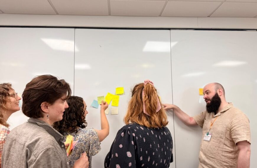 A crowd of outreach professionals stood in front of a post-it note board